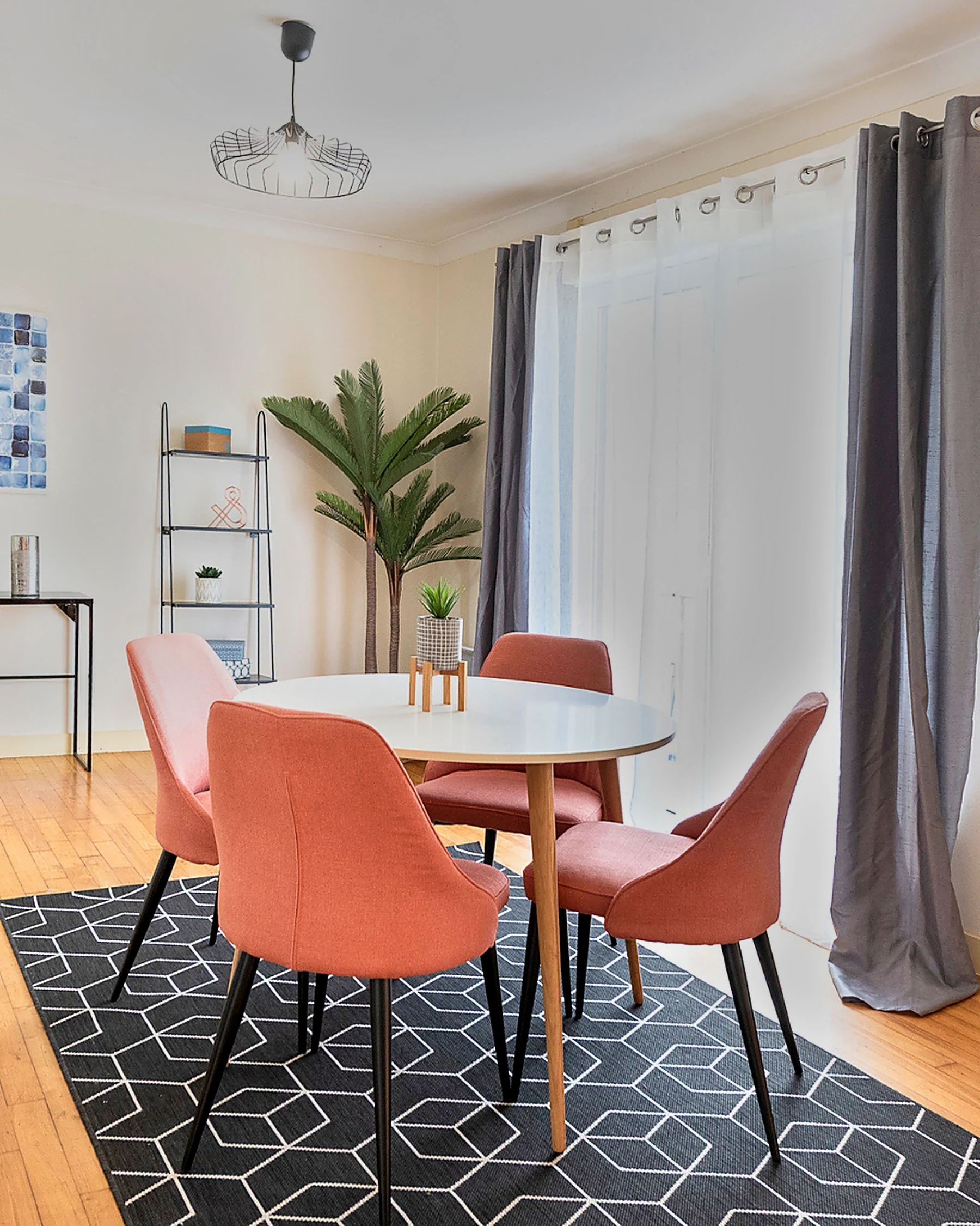 Salle à manger après home staging, table ronde blanche, chaises terracotta et tapis graphique noir et blanc