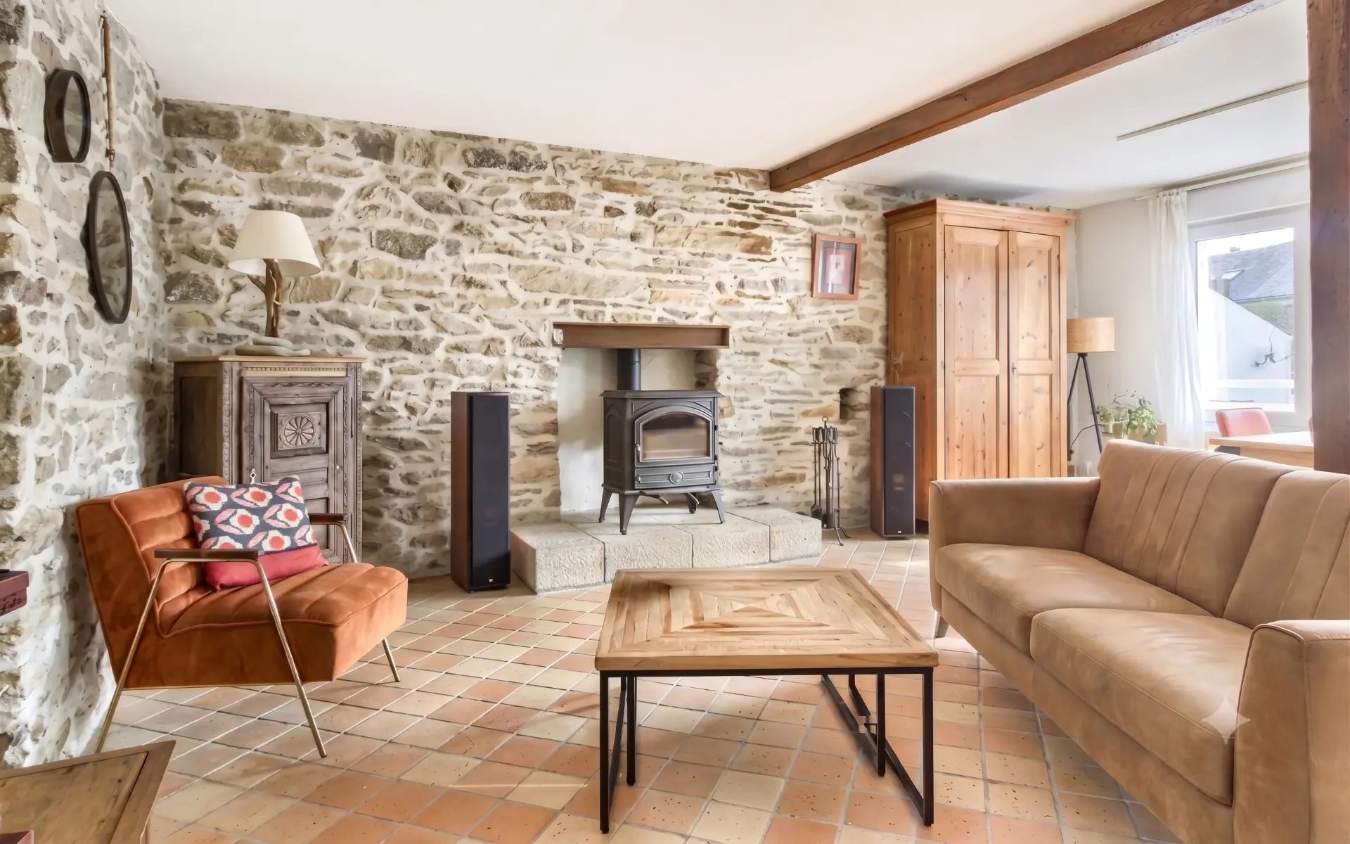 Séjour d'une maison vendue à Missillac : mur en pierre, poêle à bois et tomettes